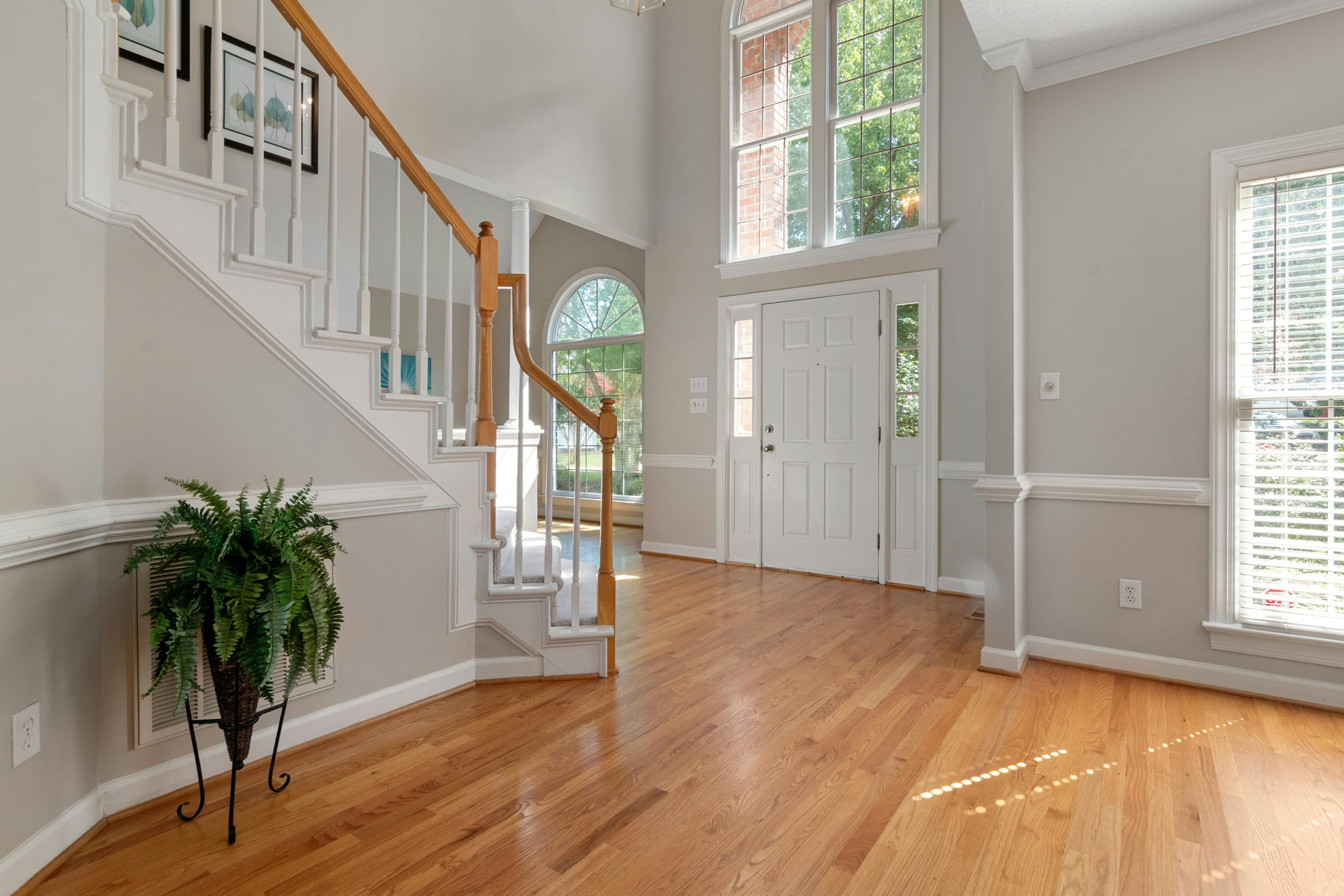 Bright two-story entry foyer with hardwood floors and staircase