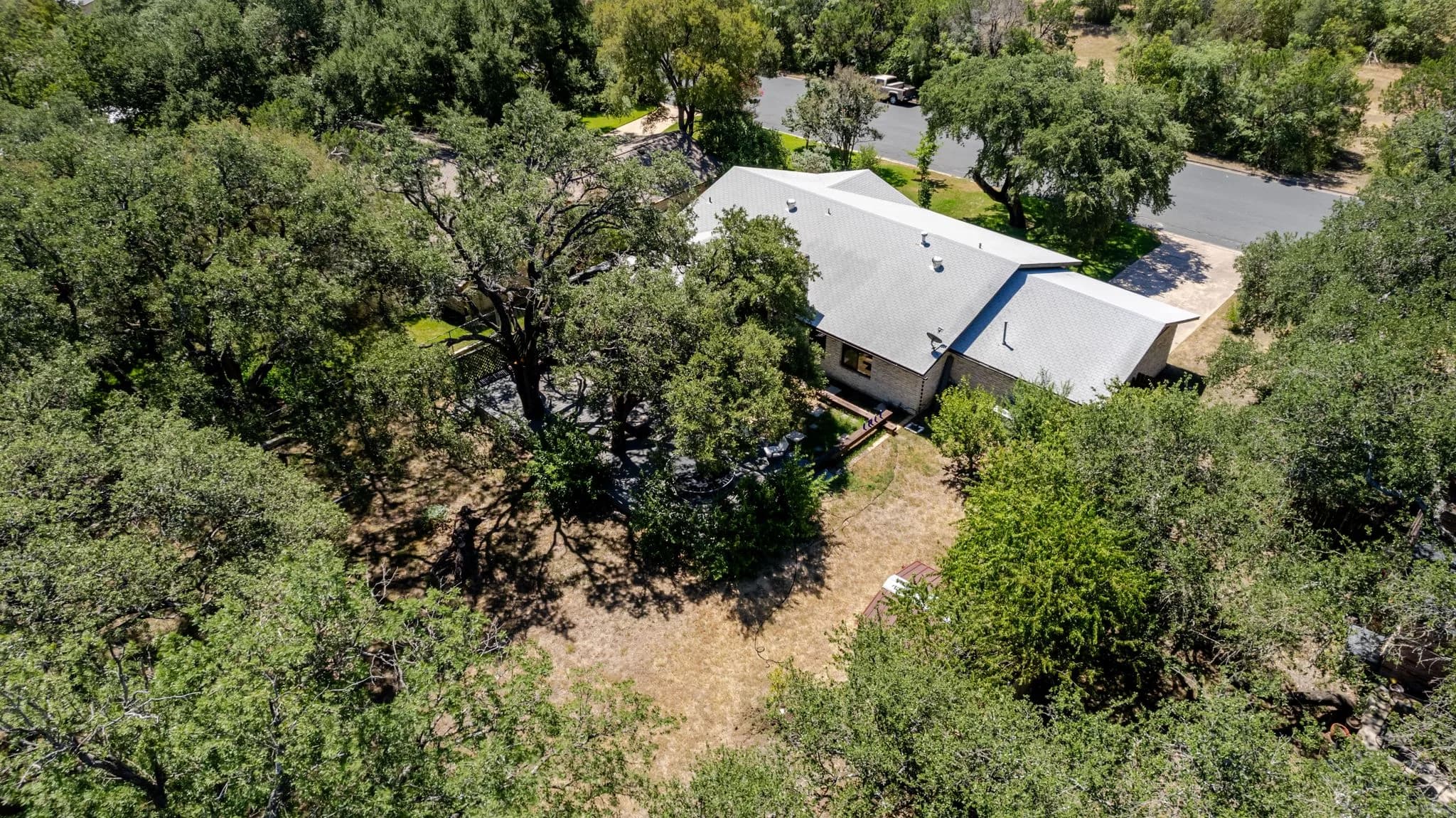 Drone view looking down over a home tucked into an oak canopy