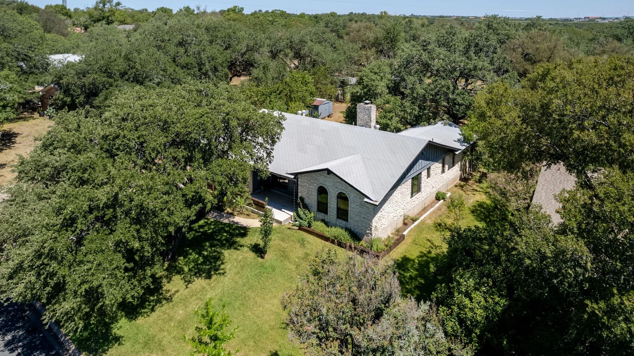 Aerial of a home on a wooded lot surrounded by oak trees