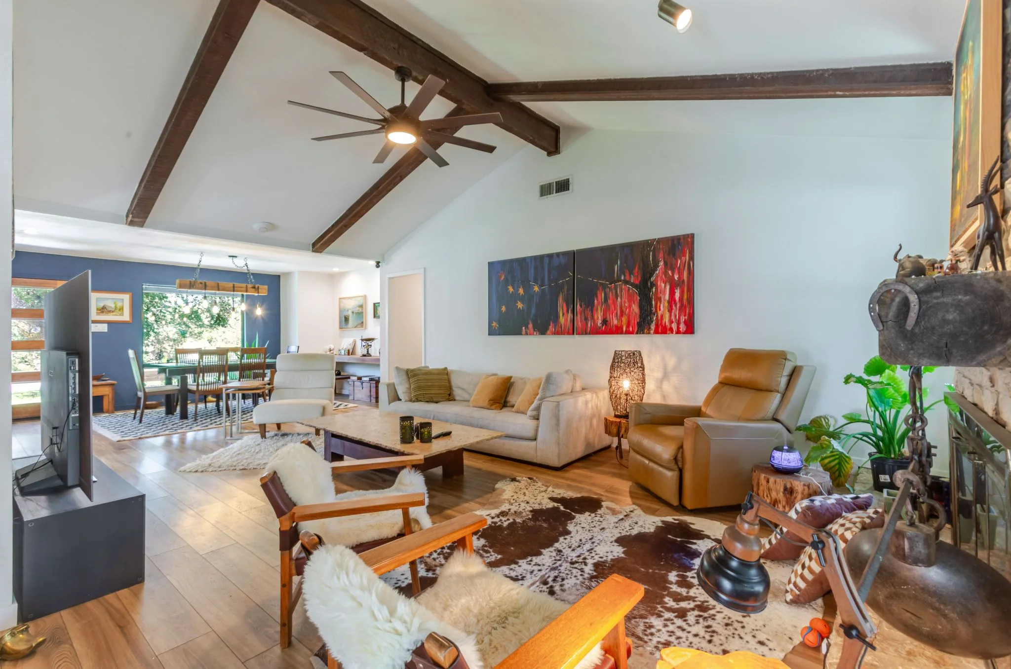 Living room with leather chairs, a cowhide rug, and beamed ceiling