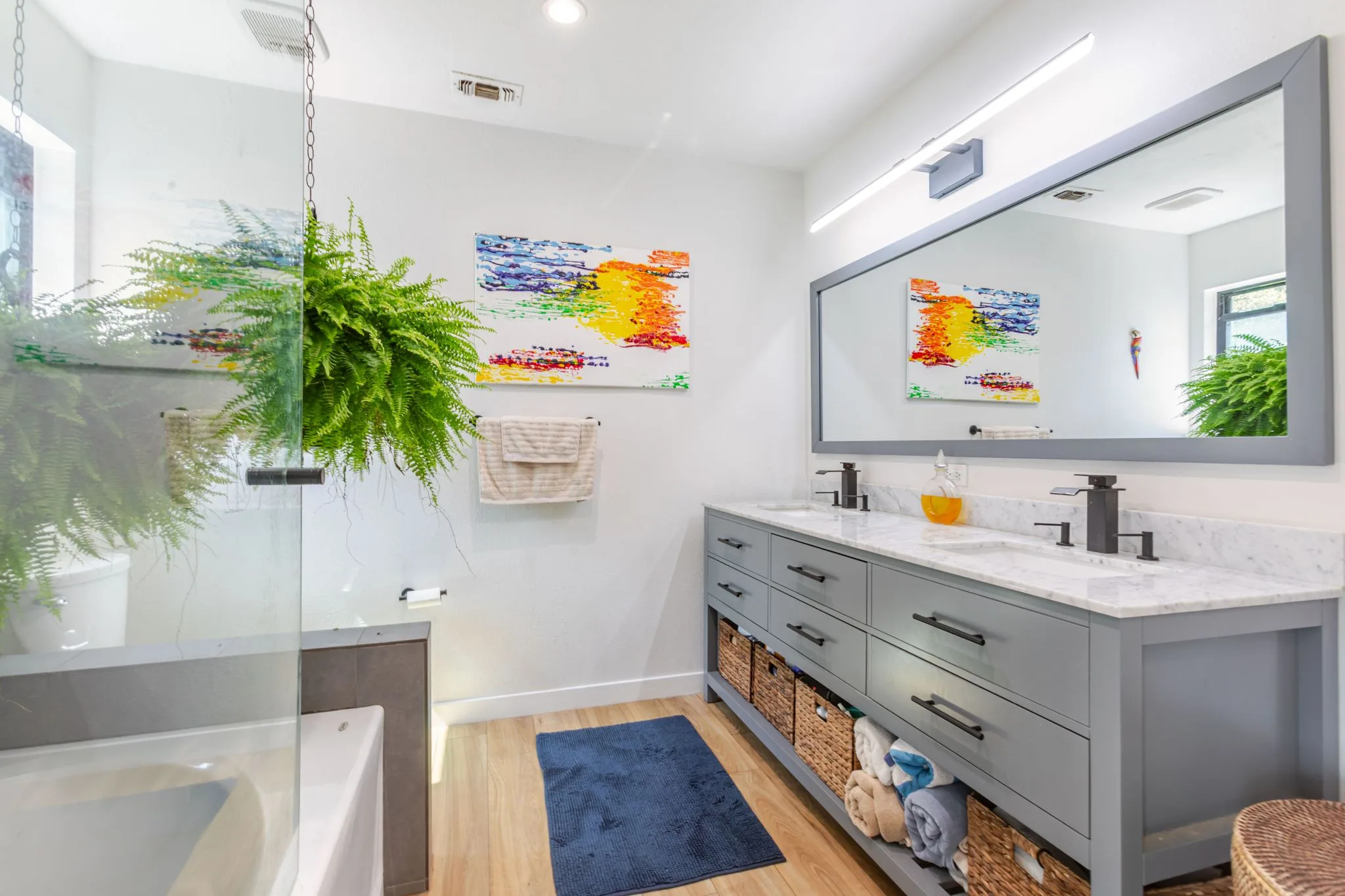 Bathroom with a double vanity, large mirror, and hanging plant